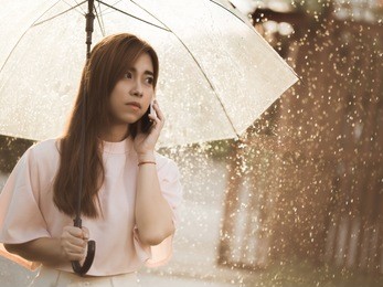 asian woman she was on the phone in the rain alone.