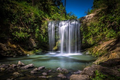 long exposure of oakley creek waterfall on a bright summers day, auckland, new zealand