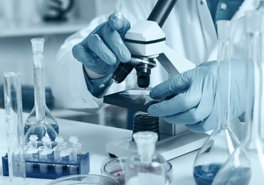 woman in a laboratory microscope with microscope slide in hand.toned image.
