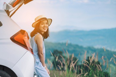 woman traveler sitting on hatchback car with mountain background in vintage tone