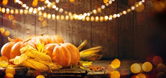 happy thanksgiving day background, wooden table decorated with pumpkins, corncob, candles and autumn leaves garland. beautiful holiday autumn festival concept scene fall, harvest