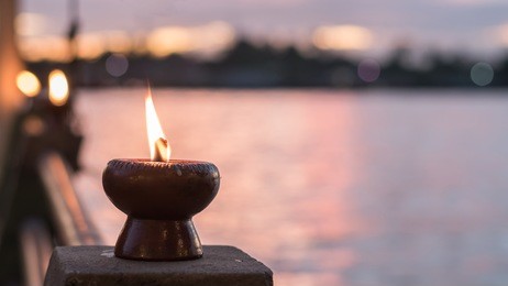 soul and spirituality abstract concept  for mourning and world human spirit day with warm candle light bokeh illumination, golden sunset sky and reflective river wave background