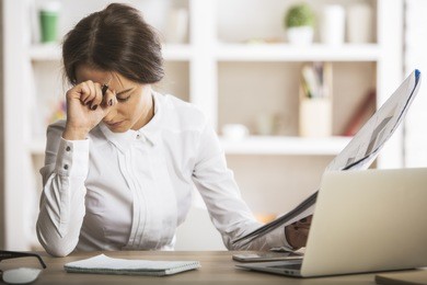 stressed young woman doing paperwork at modern workplace. stress concept