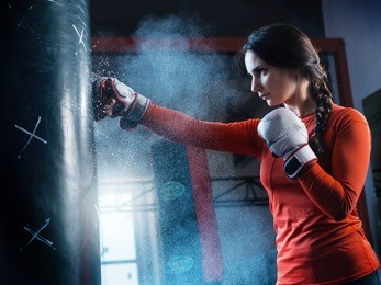 young woman training punch boxing gloves for punching bag. girl making strong kick. crossfit.