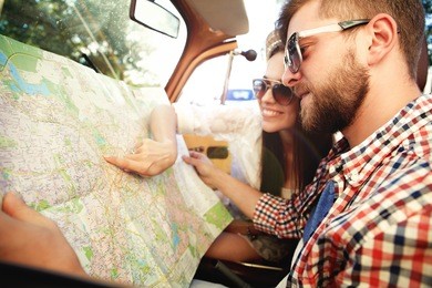young loving couple planning their romantic adventure. joyful young couple smiling while riding in their convertible