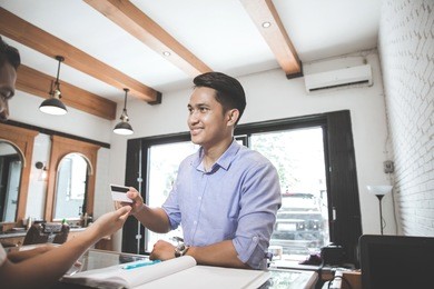 portrait of a man paying using credit card in barbershop