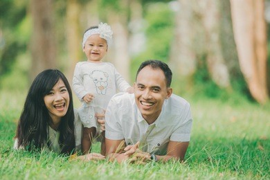 happy family of three lying in the grass in autumn