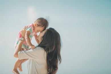 portrait of happy mother and baby girl playing at seaside