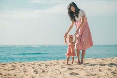portrait of a mother is teaching her daughter walks on the beach