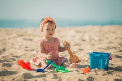 cute baby girl playing with beach toys on tropical beach