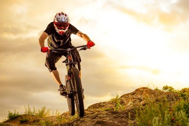 professional cyclist riding the bike down rocky hill at sunset. extreme sport concept. space for text.