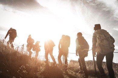 group of hikers walking on a mountain at sunset