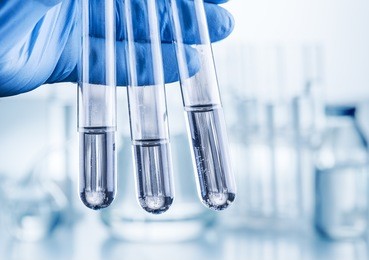 laboratory beakers in analyst's hand in plastic gloves.