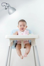 portrait of cute baby toddler sitting with dining table laughing,asian baby