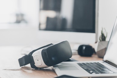modern technologies. close-up of vr headset laying on the office desk and near laptop and computer