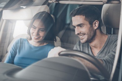 look at this console! beautiful young couple sitting at the front seat of the car checking out the side panel