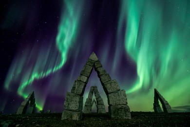 a colorful night with aurora borealis flying over the stonehenge iceland
