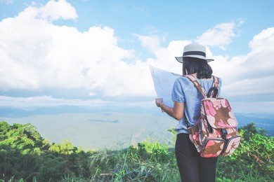woman traveler seeing on map with mountain view and cloudy sky in vintage tone