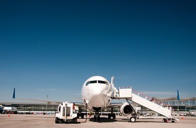 commercial airplane parked at the airport in sunny day.
front view of airplane parked at the airport and preparation for next flight. 
plane against the background of the airport. aircraft maintenance