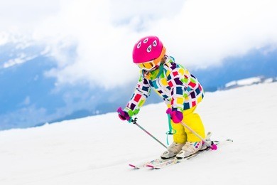 child skiing in mountains. active toddler kid with safety helmet, goggles and poles. ski race for young children. winter sport for family. kids ski lesson in alpine school. little skier racing in snow