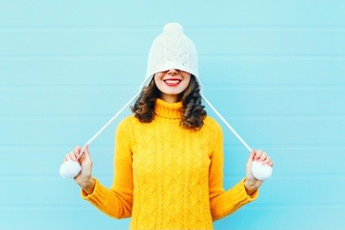fashion happy young woman in knitted hat and sweater having fun over colorful blue background