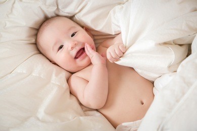 young mixed race chinese and caucasian baby boy having fun in bed.