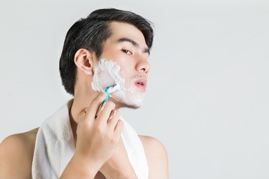 asian man is shaving, white isolated