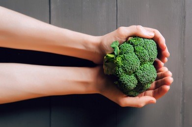 broccoli in hands. a wooden background. healthy eating concept.