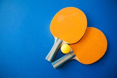 two table tennis or ping pong rackets and balls on a blue table 