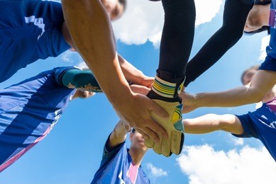 blurred image of soccer players hands together join team energy for full power that makes winners