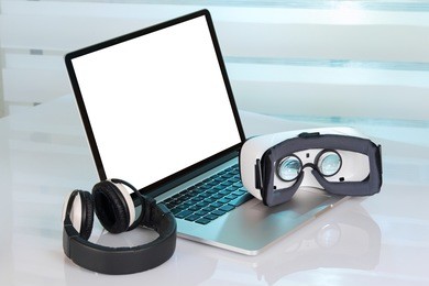 computer with blank screen and virtual reality glasses with headphones / desktop with virtual reality equipment