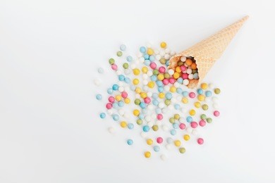 waffle cone and heap colorful candy on white background from above. flat lay style