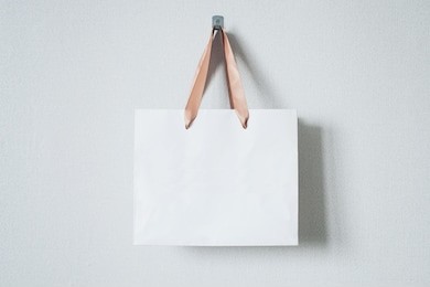 mock-up of blank craft package, mockup of white paper shopping bag with handles on the neutral background