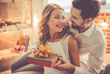 beautiful young couple is celebrating at home. handsome man is giving his girlfriend a gift box