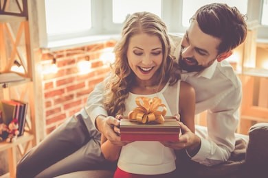 beautiful young couple is celebrating at home. handsome man is giving his girlfriend a gift box