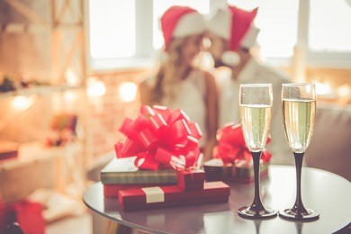 gift boxes and glasses of champagne on the table, beautiful couple celebrating christmas at home