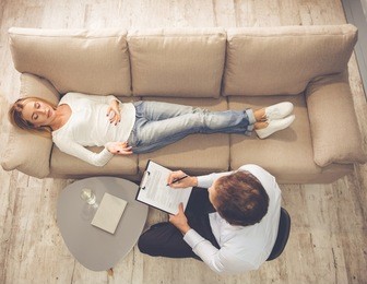 at the psychologist. top view of beautiful young woman lying on couch while doctor is making notes