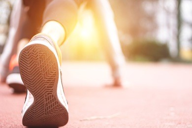 close up on running shoe of a young man having runner stretching before the run - athlete preparing position to start a run 