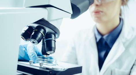 young scientist looking through a microscope in a laboratory. young scientist doing some research.