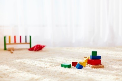 wooden toy bricks strewn on the carpet in playroom, at sunny day