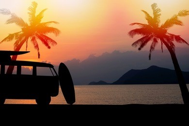 silhouette vintage car in the beach with a surfboard on the roof.