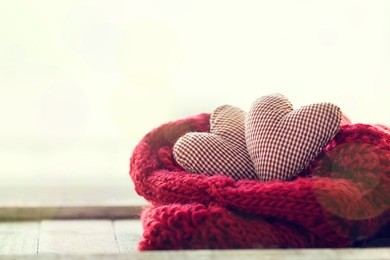 beautiful red plush hearts with warm scarf on a bright background, horizontal. home, winter, valentine's day or love concept