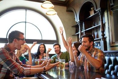 people, leisure, friendship and entertainment concept - happy friends drinking beer, watching sport game or football match and celebrating victory at bar or pub