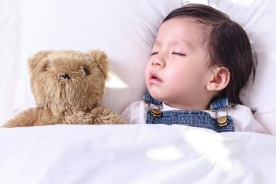 kid asian girl sleeping with her teddy bear on the bed, new family and baby healthy concept