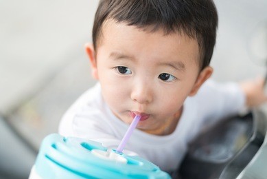 close up of asian baby boy drinking water with straw, shallow dof