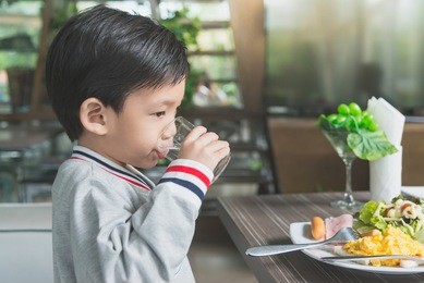 cute asian child drinking water in the glass