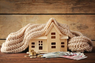 plywood toy house with warm scarf and money on wooden background