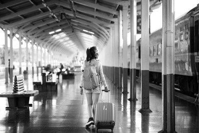 a young traveler girl with camera and luggage at train station.black and white.