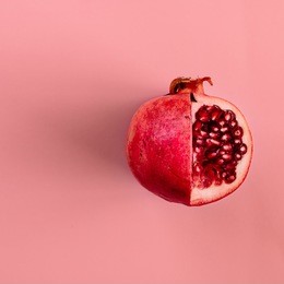 red pomegranate fruit on pastel pink background. minimal flat lay concept.