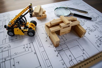 toy construction machine builds model of house from wooden blocks (bars) at the drawings.